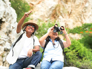 Boyfriend pointing while sitting with girlfriend against mountain