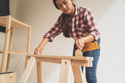 Full length of young woman standing against wall at home