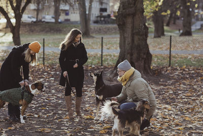 Full length male and female pet owners with dogs at park