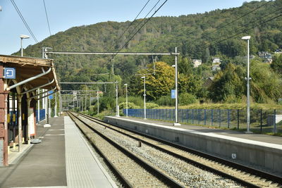 Railroad station platform by trees against sky