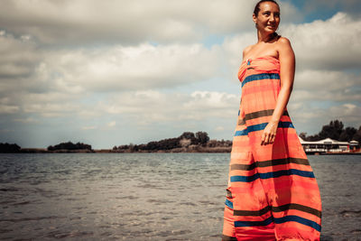 Woman standing at beach against sky