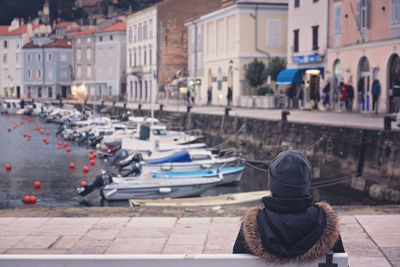 Rear view of woman sitting against canal in city