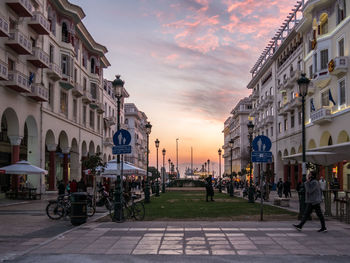 People on street amidst buildings in city against sky