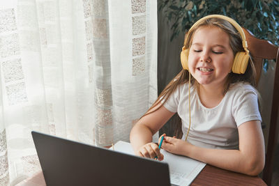 Little girl uses a laptop and shows her teeth and smile to study at home with  a speech therapist. 