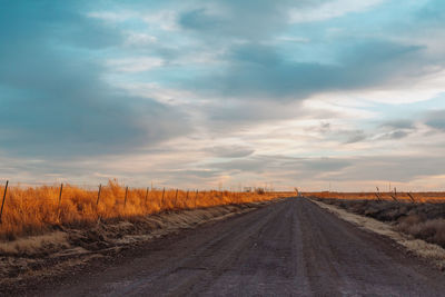 Road amidst field against sky