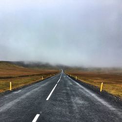 Empty country road along landscape against clear sky