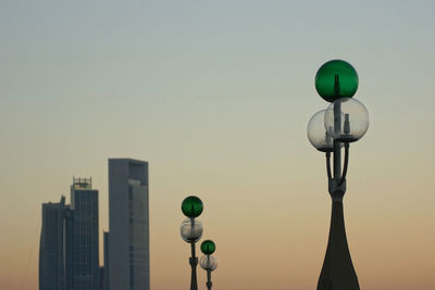 Low angle view of street lights and buildings against clear sky at sunset