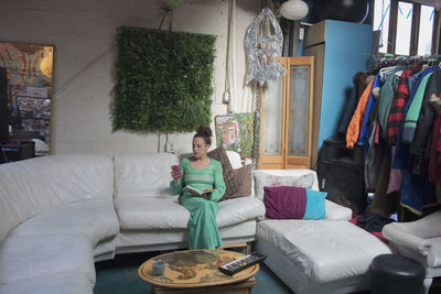 Young woman sitting on living room couch reading a book