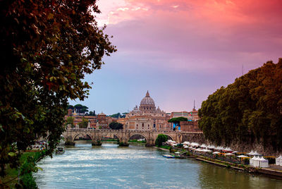 River amidst buildings against sky during sunset