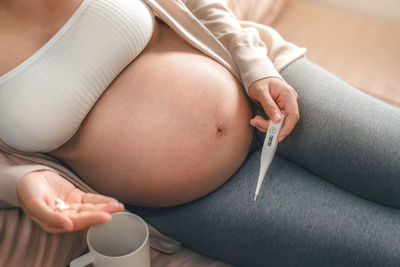 Midsection of woman holding baby while sitting at home