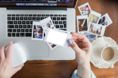 Woman holding in hands instant photo with place for photo of your choice