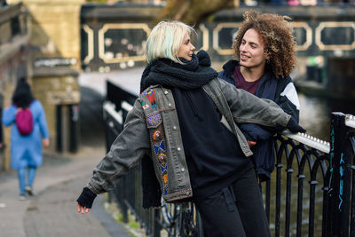 Young couple talking while standing by railing in city