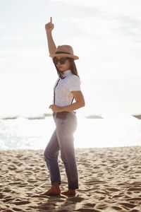 Portrait of woman wearing sunglasses while standing at beach