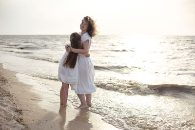 Friends standing on beach against sea