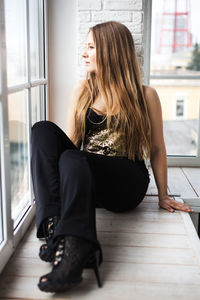 Full length of woman sitting on chair at home