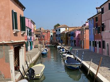 Boats moored in canal amidst buildings against sky