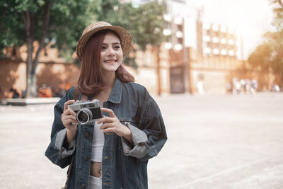 Portrait of young woman photographing on street