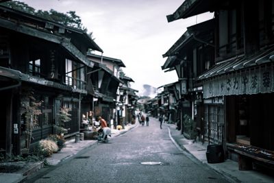 People walking on street amidst buildings in city