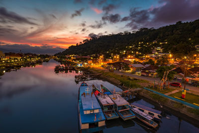 High angle view of illuminated city by river against sky