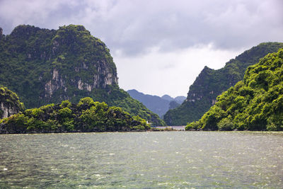 Scenic view of river by mountains against sky