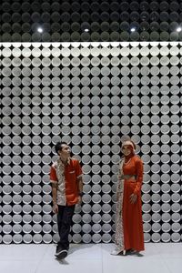 Full length of couple standing against patterned wall