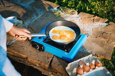 High angle view of man preparing omelet food on camping stove