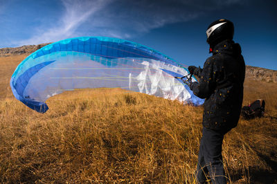 Paraglider lands or rises on the yellow grass on a sunny day. a man after or before a paragliding