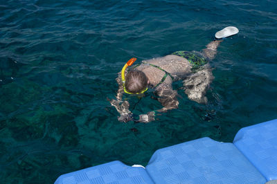 Plump girl in a green swimsuit and a swimming mask, dives and swims in the sea