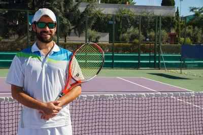 Portrait of smiling tennis player standing in court