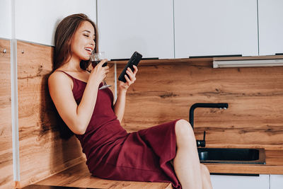 Young woman sitting on hardwood floor at home