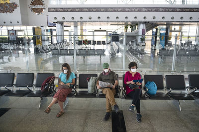 Family of three wearing face masks due to the coronavirus global health crisis while waiting at a deserted airport in khajuraho, madhya pradesh, india.