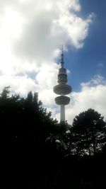 Low angle view of communications tower against cloudy sky