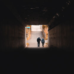 Rear view of people walking in tunnel