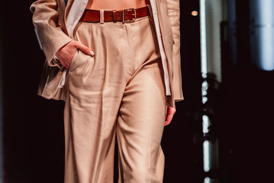 Fancy details of stylish neutral beige outfit, classy jacket, pants with leather brown belt