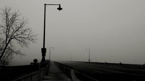 Street light on bridge against sky during foggy weather