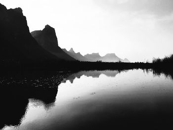Scenic view of lake by silhouette mountain against sky