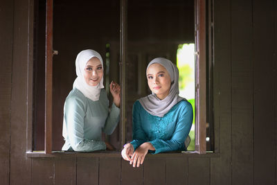 Portrait of two women sitting on door