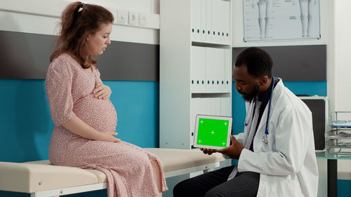 Doctor showing digital tablet to pregnant woman