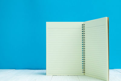 Open book on table against blue wall