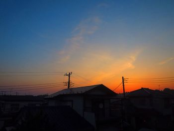 Silhouette houses against sky during sunset