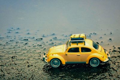 High angle view of yellow toy car on sand