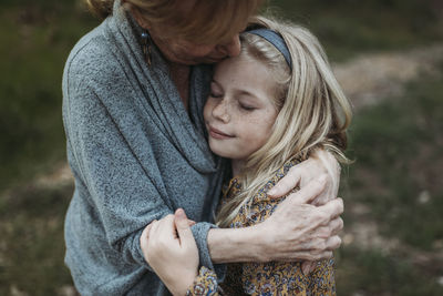 Detail image of young girl being hugged by senior grandmother