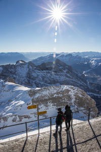High angle view of people looking at snow covered mountain during sunny day