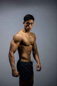 Portrait of shirtless man standing against white background