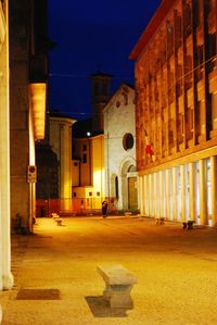 Illuminated street amidst buildings in city at night