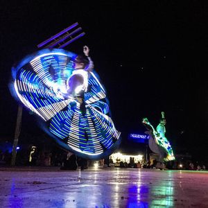 Illuminated ferris wheel against blue sky