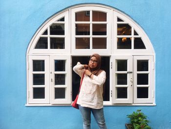 Woman in hijab standing against window