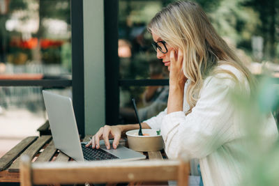 Business woman working remotely while sitting in a cafe in summer.