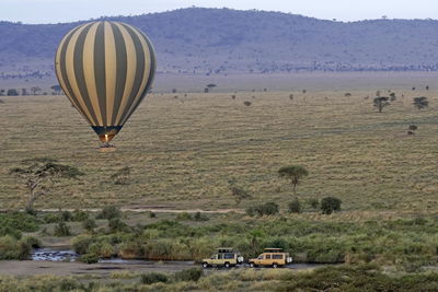 Hot air balloon over river with hippos in serengeti national park