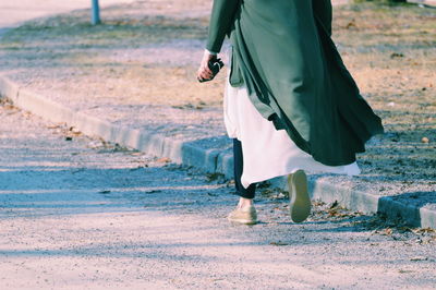 Low section of woman walking on road